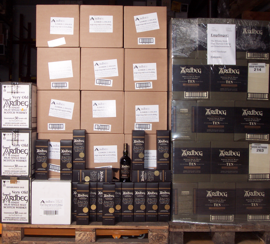 left pallet of ardbeg in brown boxes with a few bottles in front, right a pallet of Ardbeg TEN